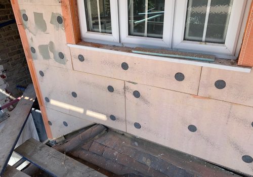 Close-up of EWI installation process showing solid wall insulation boards being fitted in the London area.